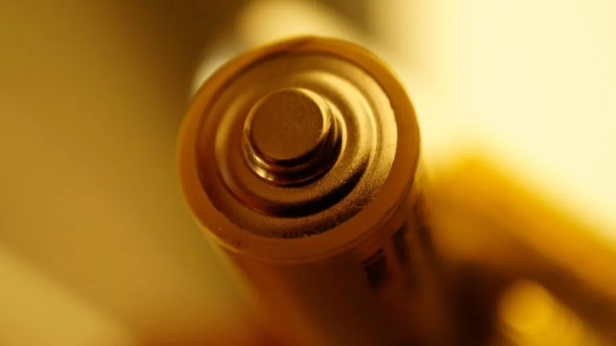 Close-up of hands holding small batteries and electronic devices in natural lighting