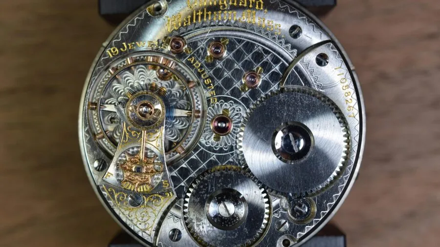 Close-up of hands inspecting the internal movement mechanism of a vintage pocket watch