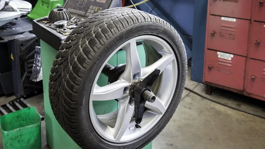 Close-up of hands inspecting tire valve stem and cap during vehicle maintenance check