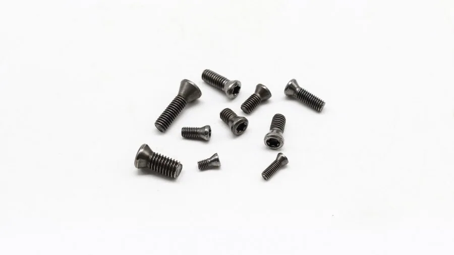 Close-up of hands installing cabinet hardware with screws on wooden cabinet door