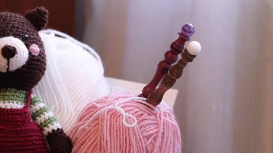 Close-up of hands knitting with natural wool yarn, showing texture and craftsmanship in warm lighting