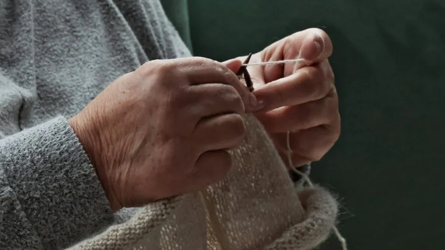 Close-up of hands knitting with proper posture and ergonomic positioning during extended crafting session