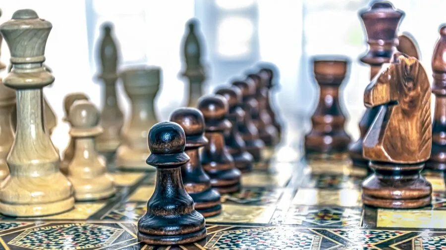 Close-up of hands moving wooden chess pieces on board during game
