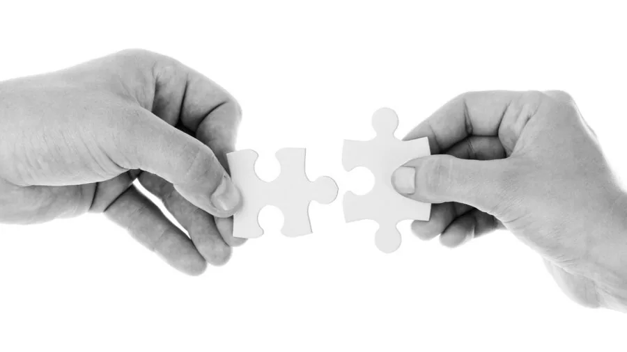 Close-up of hands placing puzzle pieces together on a felt surface during a puzzle-solving session