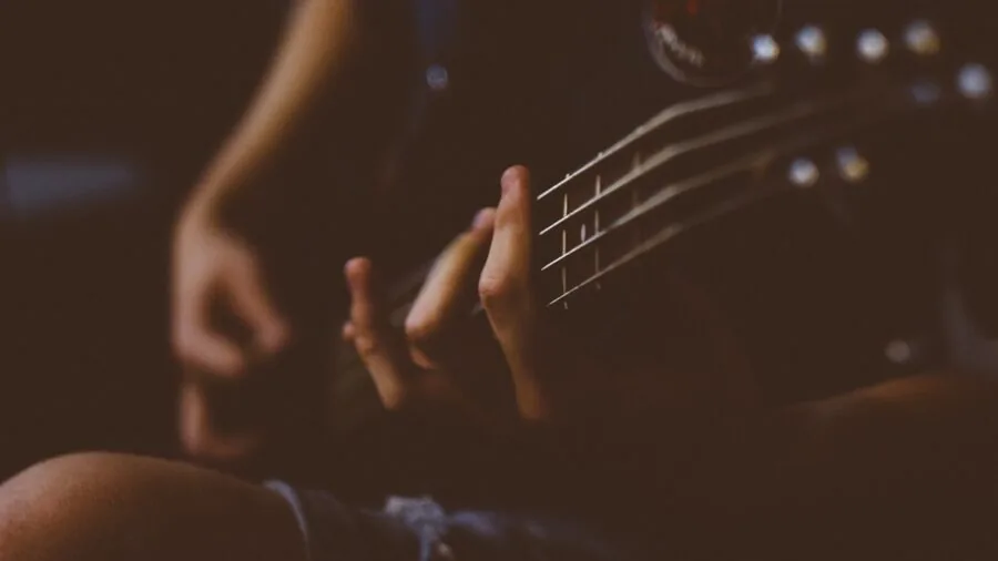 Close-up of hands playing an acoustic guitar, focusing on the wooden soundboard and strings during performance