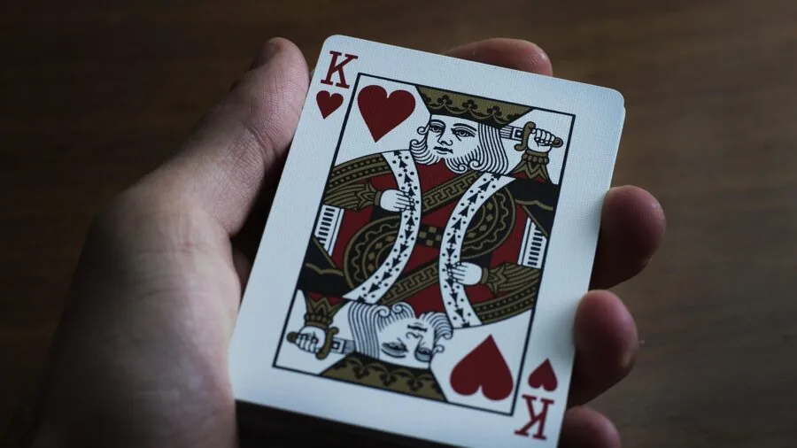 Close-up of hands playing dominoes on wooden table during casual game night with friends