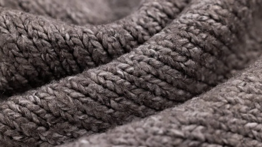 Close-up of hands touching soft breathable fabric material in natural daylight