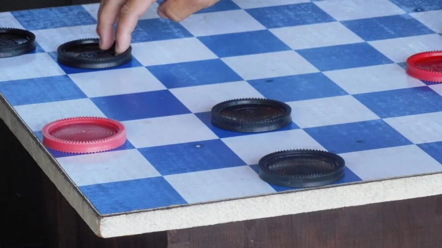 Close-up of hands touching wooden game pieces during strategic board game play session