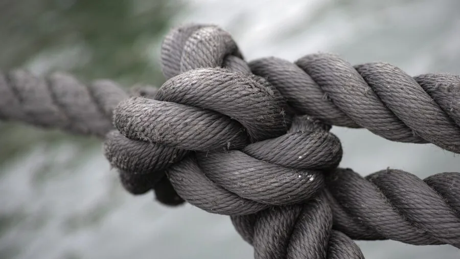 Close-up of hands tying secure knots on camping gear outdoors