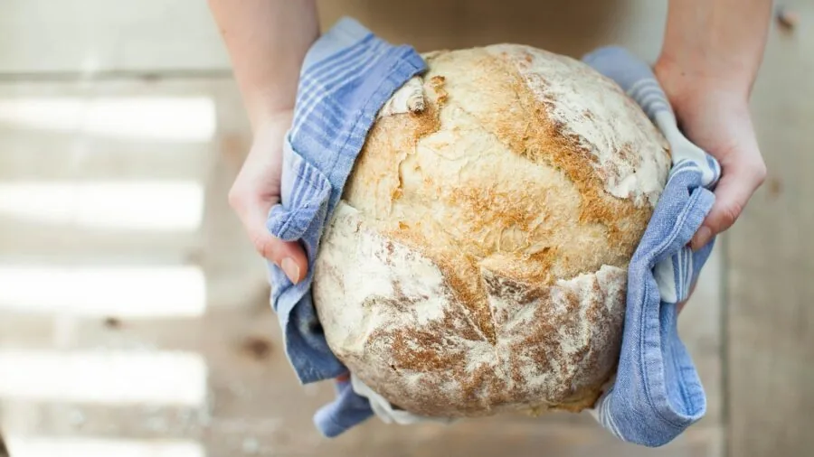 Close-up of hands using measuring cup to scoop flour into a bowl during home baking