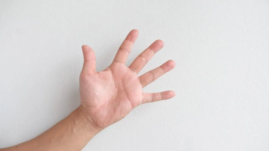 Close-up of hands using sharp scissors to cut colorful fabric on a wooden table