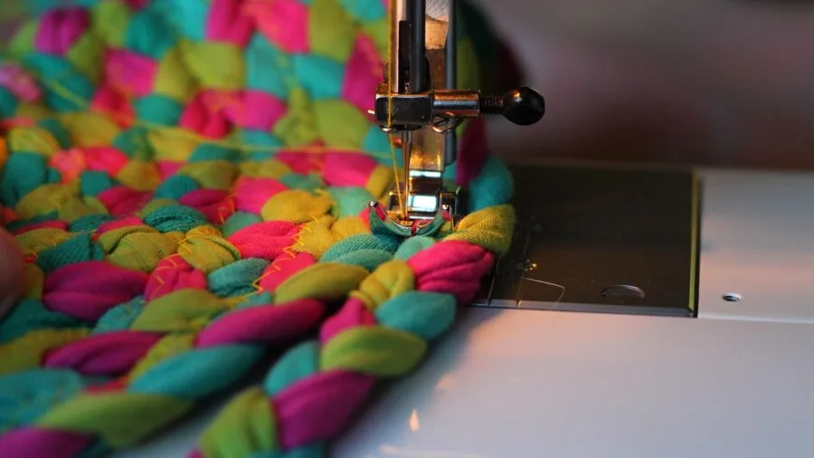 Close-up of hands working with delicate rolled hem on fabric during sewing project