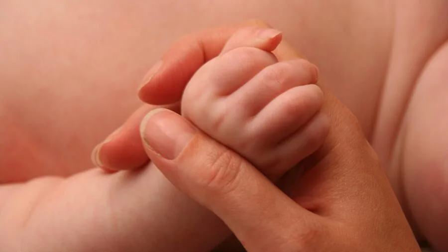 Close-up of infant's wet hand grasping during bath time, showing small fingers and developing motor control