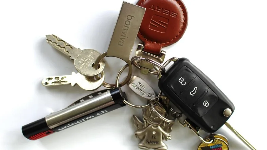 Close-up of keys on a keyring attached to a car ignition, showing everyday carry items in natural light