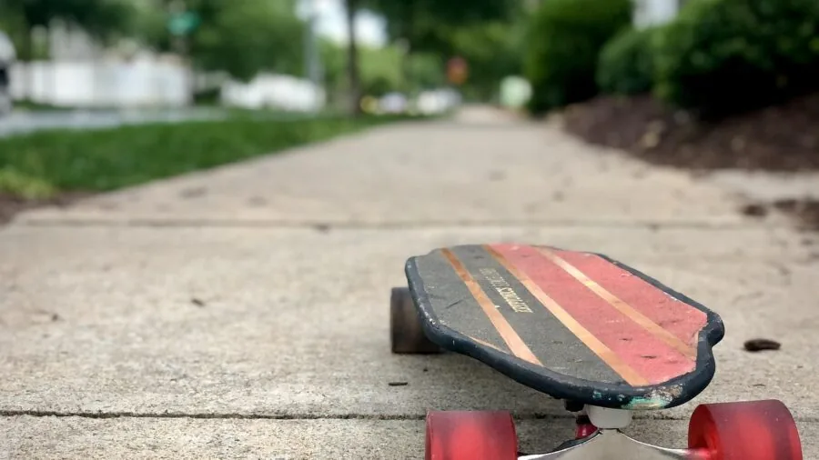 Close-up of longboard wheels rolling smoothly across textured pavement during outdoor ride