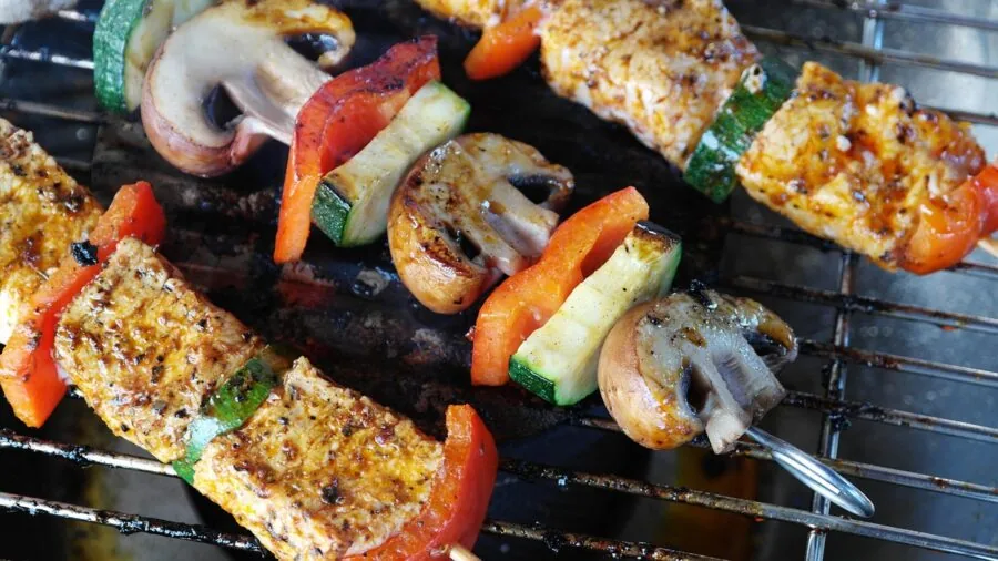 Close-up of meat cooking on a ridged grill pan with char marks and smoke