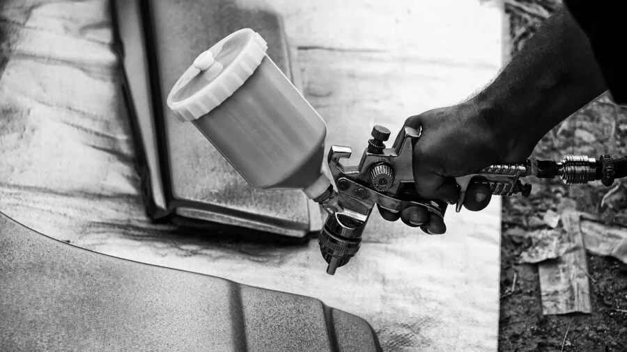 Close-up of mechanic's hands with strong grip on metal wrench during car maintenance work
