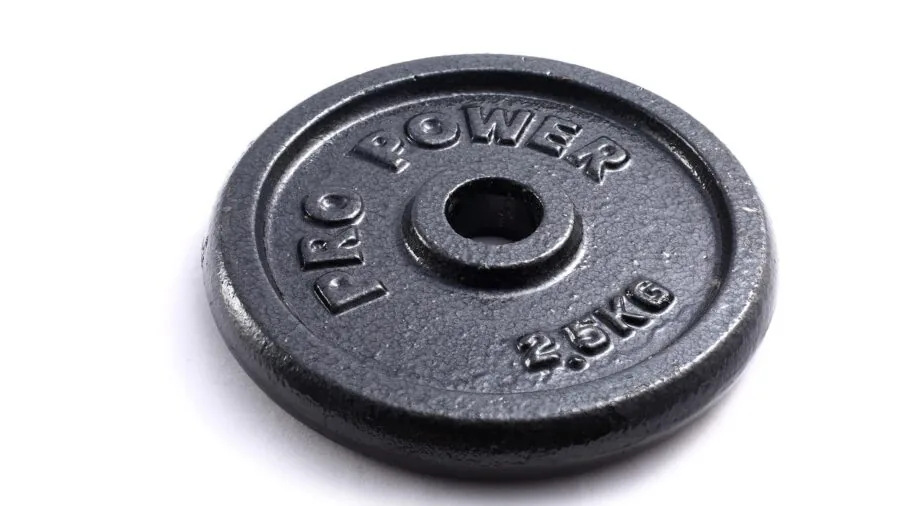 Close-up of Olympic barbell plates loaded on a weightlifting bar in a home gym setting