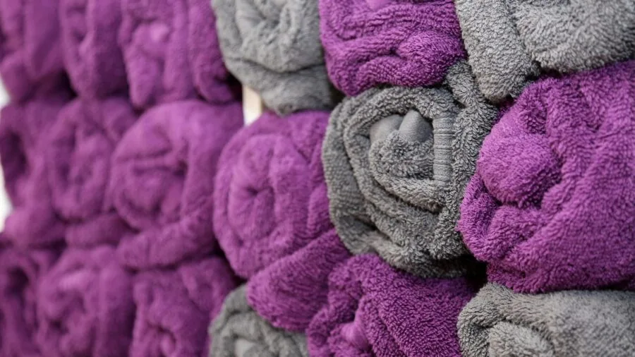 Close-up of plush bath towel fabric showing soft texture and absorbent weave in warm bathroom lighting