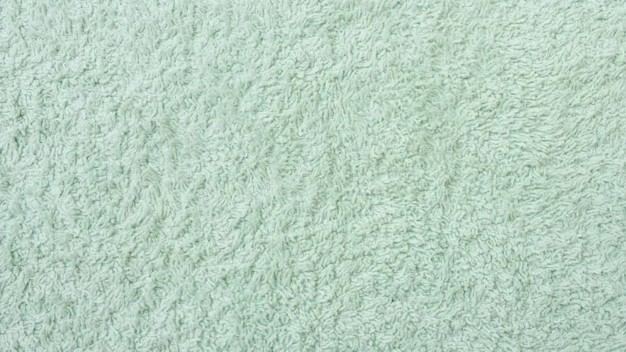 Close-up of plush white towel fabric showing texture and density for bathroom use
