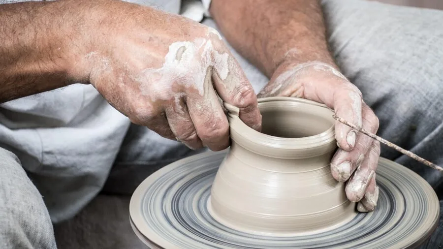 Close-up of potter's hands guiding clay on spinning pottery wheel during ceramic creation