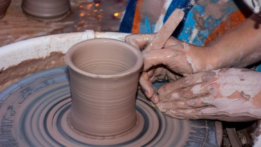 Close-up of potter's hands shaping clay on spinning pottery wheel in studio