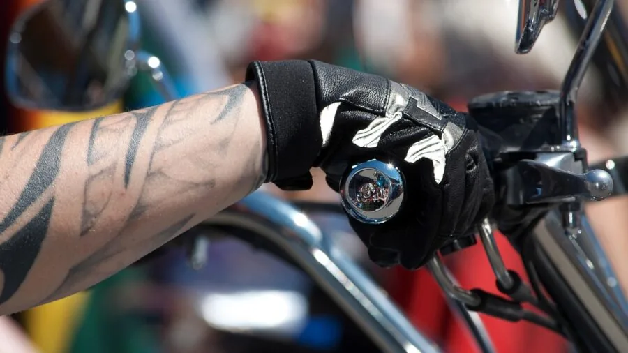 Close-up of rider's hands in durable protective gloves gripping motorcycle handlebars during ride
