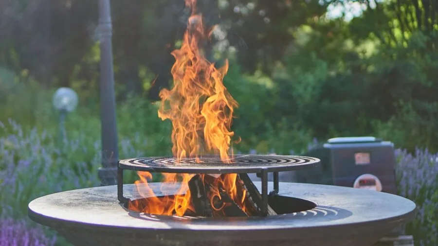 Close-up of sizzling food with deep sear marks on cast iron grill grates during outdoor cooking