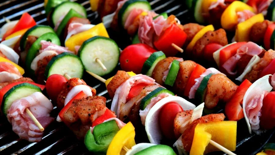 Close-up of sizzling meat cooking on a high-heat grill with visible flames and smoke