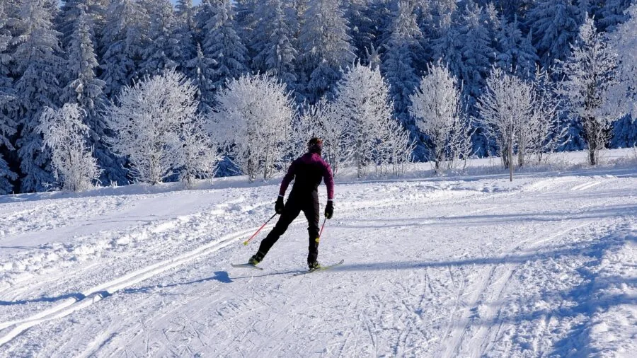 Close-up of ski pants pocket with gloved hand accessing zipper while wearing winter clothing on snowy mountain