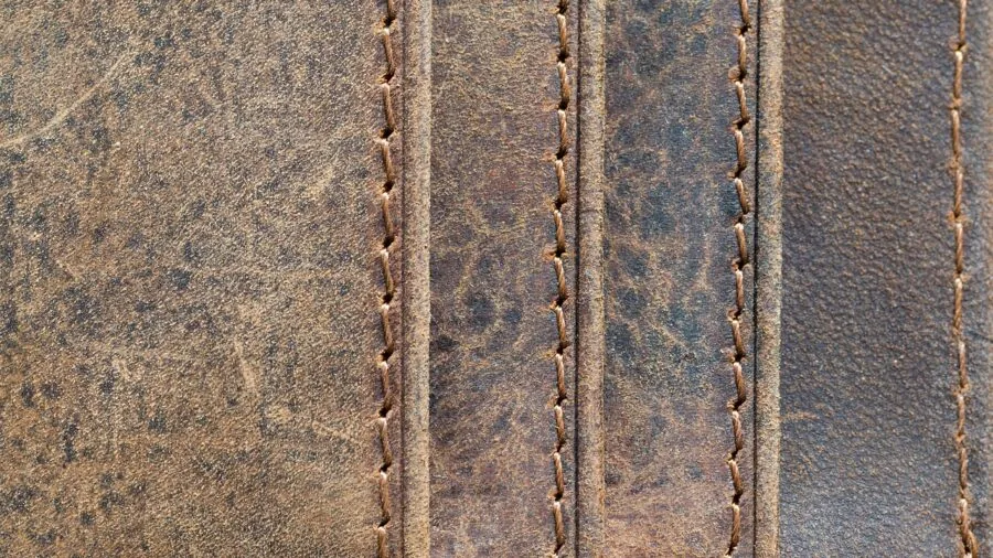 Close-up of skilled hands examining leather wallet stitching and construction quality
