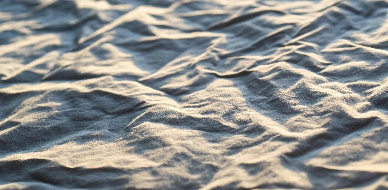 Close-up of soft white cotton sheets neatly arranged on a bed in natural light