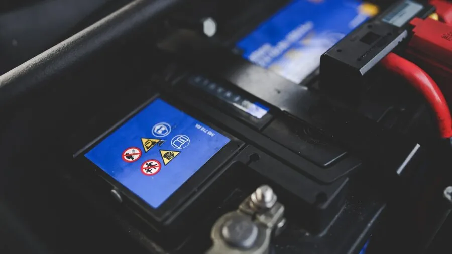 Close-up of someone inspecting a vehicle battery terminal in natural daylight