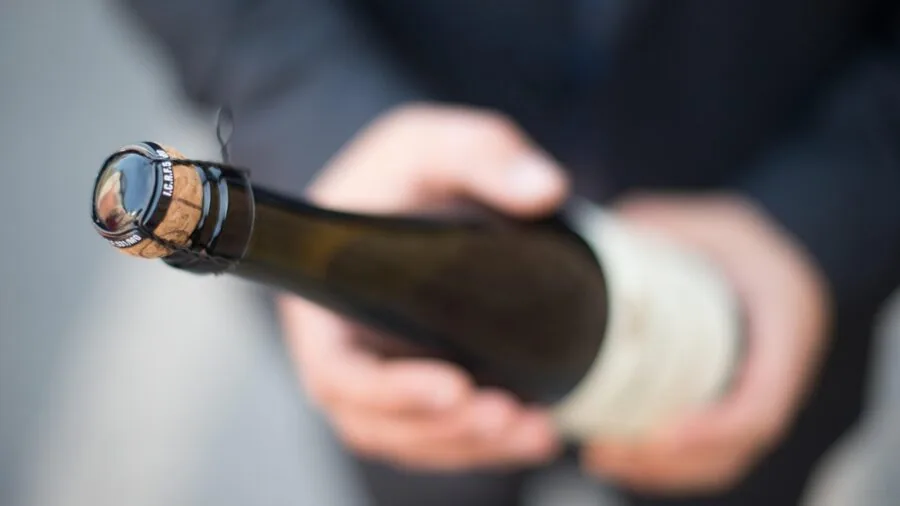 Close-up of someone's hands ergonomically opening a wine bottle during dinner preparation