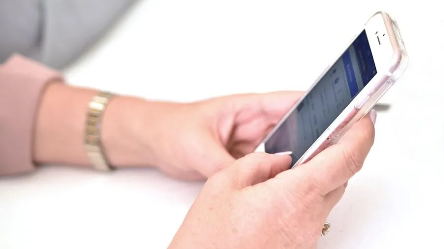 Close-up of someone's hands in fitted gloves touching a smartphone screen outdoors in winter