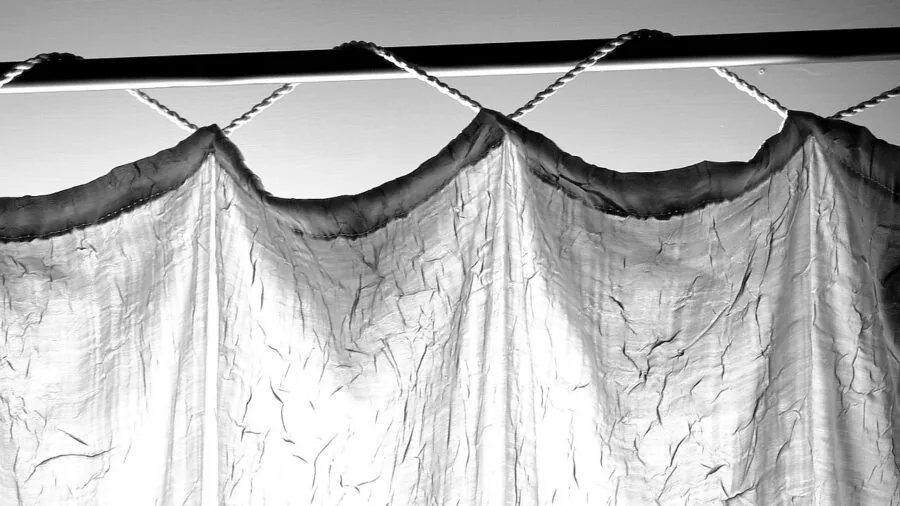 Close-up of thick fabric draped on a metal curtain rod showing weight and support in a bright living room