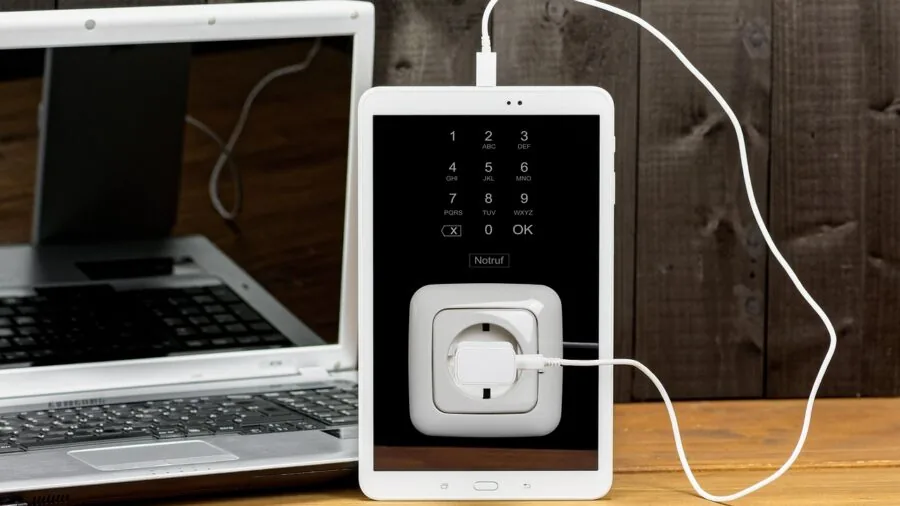 Close-up of various USB cables and charging ports connected to a laptop on a wooden desk