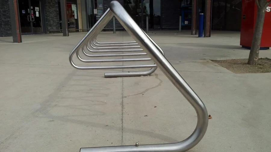 Close-up of weathered steel bike rack showing powder coating durability in outdoor environment