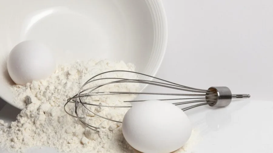 Close-up of whisking eggs in a mixing bowl during cooking preparation