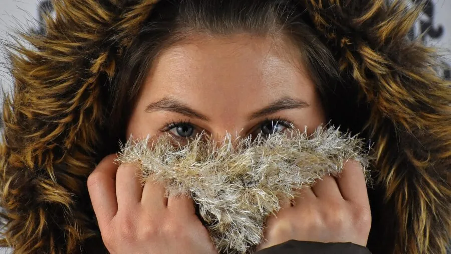Close-up of woman feeling soft wool scarf fabric against her skin outdoors
