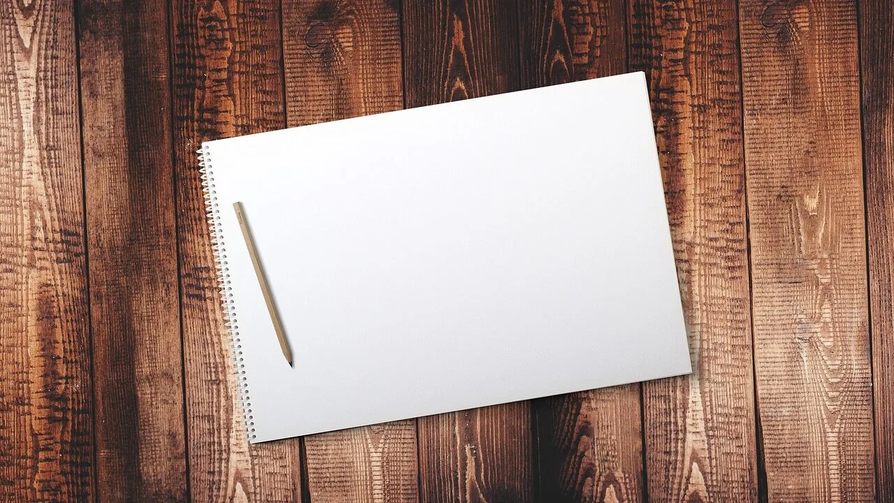 Collection of open sketchbooks with pencils and art supplies on wooden desk