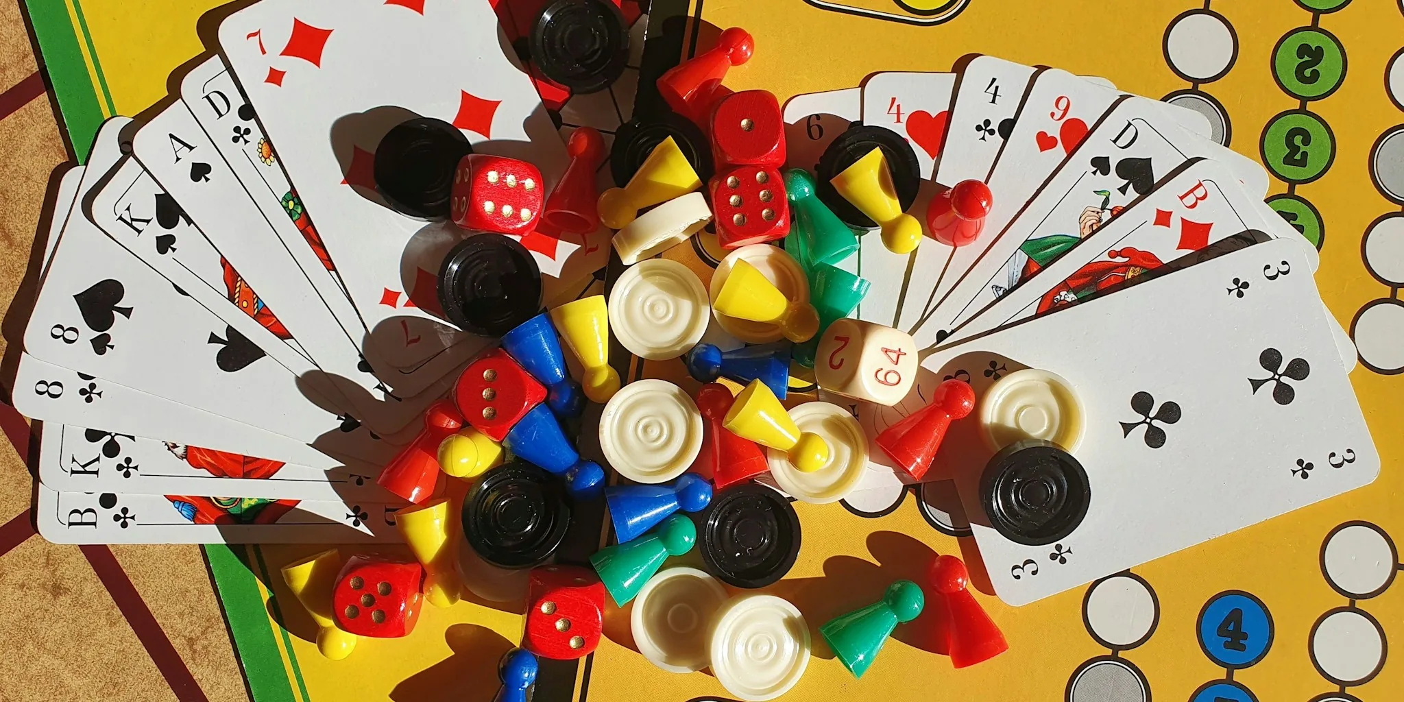 Colorful board games with pieces and dice arranged on wooden table