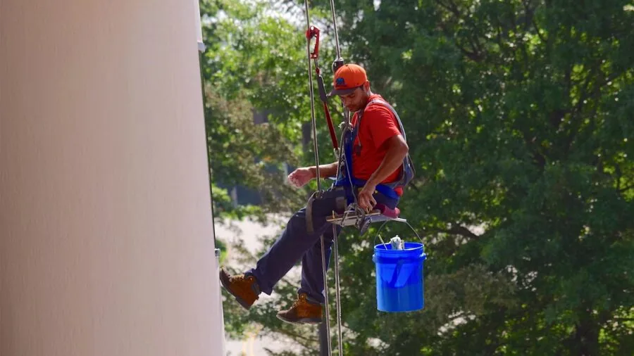 Construction worker carefully adjusting and fitting a safety harness before climbing work