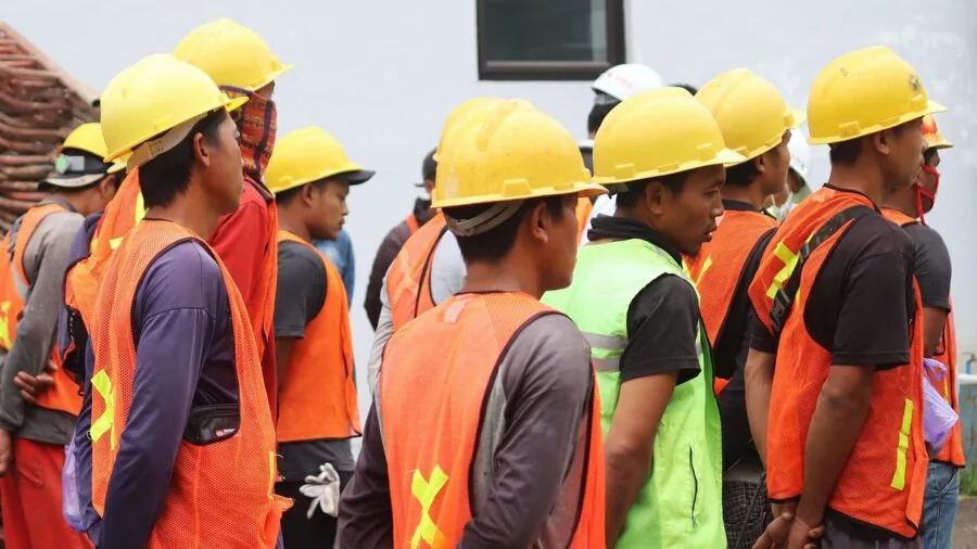 Construction worker in bright neon yellow-green safety vest on job site during daytime