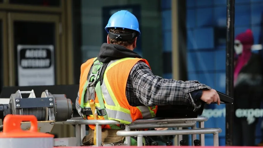Construction worker in reflective safety vest during evening work, showing visibility strips