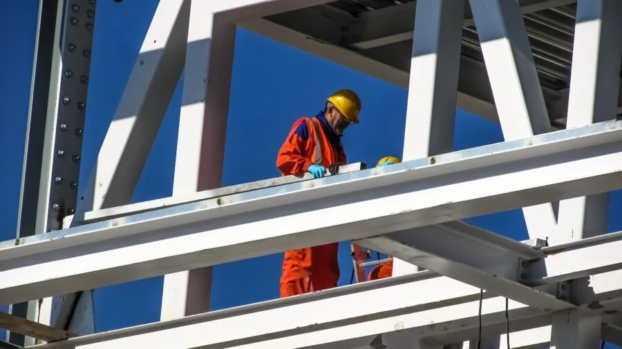 Construction worker in safety gear inspecting road work site with protective equipment visible