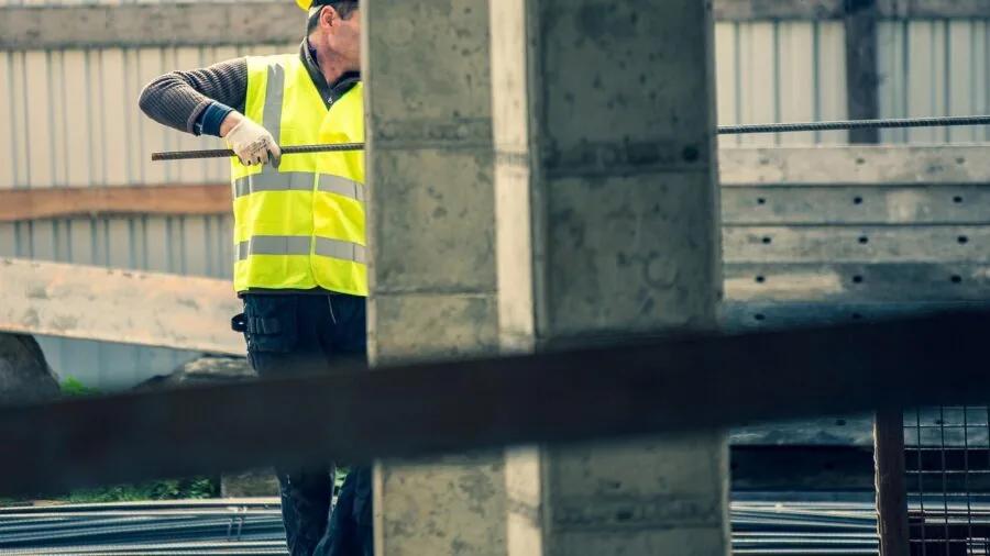 Construction worker on job site wearing protective work boots while inspecting building materials