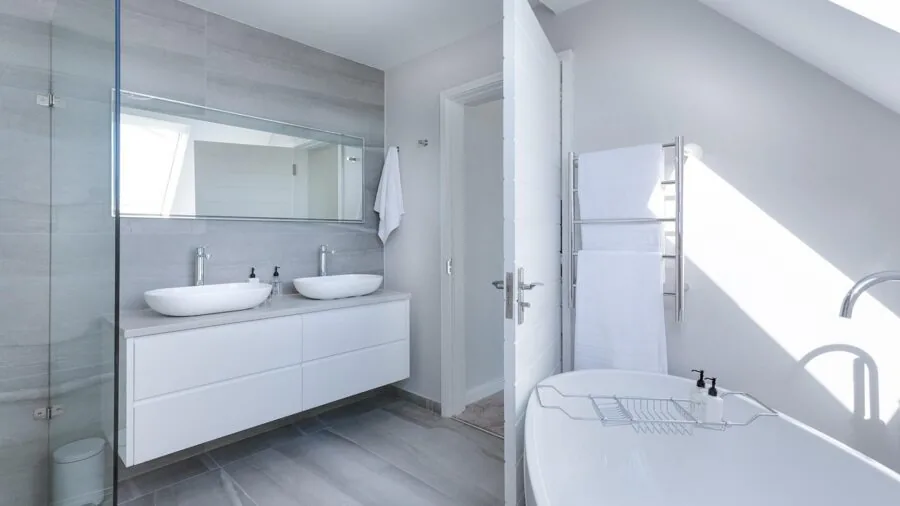 Contemporary bathroom featuring a large wall mirror above vanity with natural lighting and minimalist decor