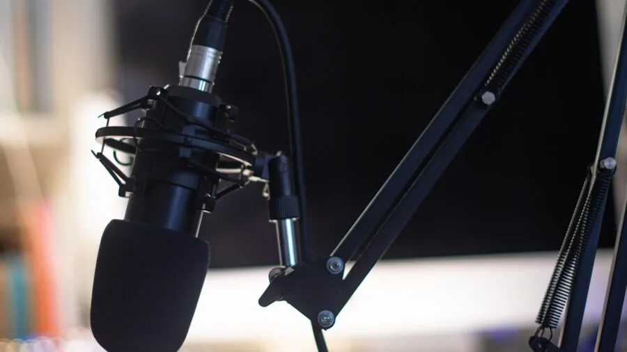 Content creator adjusting audio settings on computer while recording podcast in home studio