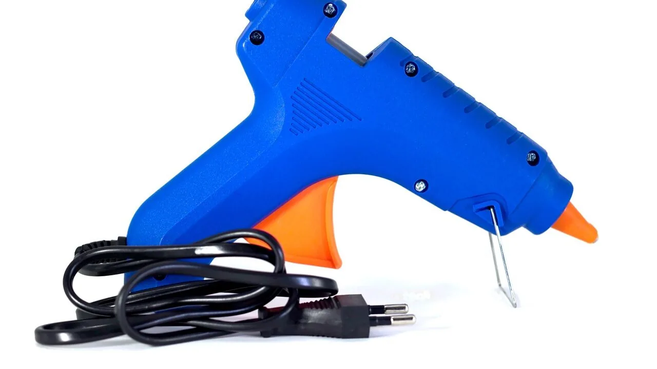 Cordless glue gun being used on craft materials with clear view of the tool in foreground